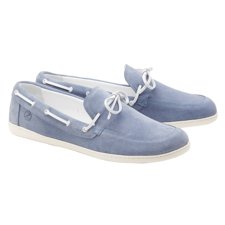 Hellblaue Mokassins aus Veloursleder mit weißen Schnürsenkeln und Sohlen von ZAQQ. Diese QEA Velours Lightblue-Schuhe zeichnen sich durch eine weiche Textur und ein Slip-On-Design aus, ergänzt durch dekorative Schnürung an den Seiten und ein kleines Emblem an der Ferse für ein elegantes Finish.