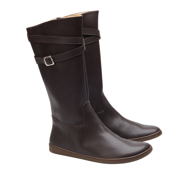 Die ATTRAQT Vegan Brown-Stiefel von ZAQQ sind kniehoch und haben einen schmalen Riemen und eine silberne Schnalle am oberen Teil. Diese Stiefel verfügen über eine flexible Sohle und weisen ein schlankes, schlichtes Design für ultimativen Komfort und Stil auf.