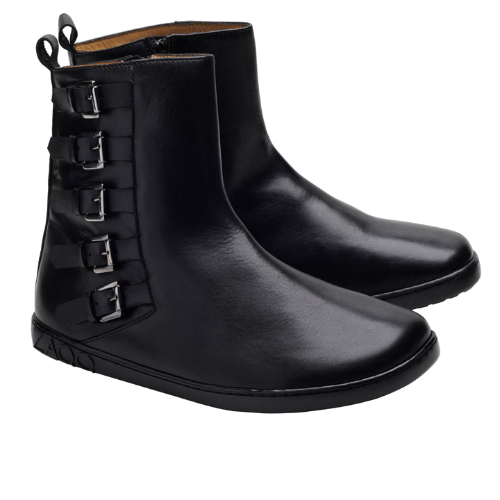 Die DANIQ Black Boots von ZAQQ sind elegante schwarze Lederstiefeletten mit vier seitlichen Schnallen im Biker-Boot-Stil und einem seitlichen Reißverschluss auf weißem Hintergrund. Diese aus hochwertigem Nappaleder gefertigten Stiefel bieten ein minimalistisches Design, das durch dezente Nähte hervorgehoben wird und für einen mühelos stilvollen Auftritt sorgt.