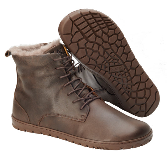 Wir präsentieren die QUINTIC Winter Brown-Stiefel von ZAQQ: ein Paar braune Stiefeletten aus Nappaleder, komplett mit kuscheligem Kunstfellfutter und strukturierter ZAQQ-Outdoorsohle. Ein Stiefel wird aufrecht präsentiert und zeigt die Seiten- und Vorderansicht, während der andere angewinkelt ist, um das einzigartige Muster der Sohle hervorzuheben.