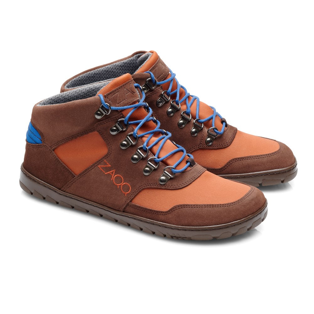 Wir präsentieren die wasserdichten HIQE Mid Terracotta-Stiefel, entworfen von ZAQQ. Diese Wanderstiefel haben ein Veloursleder-Finish in Braun und Orange, akzentuiert durch blaue Schnürsenkel und eine graue Outdoorsohle. Sie sind mit Metallösen und einem Textilfutter ausgestattet und tragen stolz den Markennamen auf der Seite. Die sorgfältigen Nähte und das Design sorgen für Haltbarkeit und Komfort bei jedem Abenteuer.