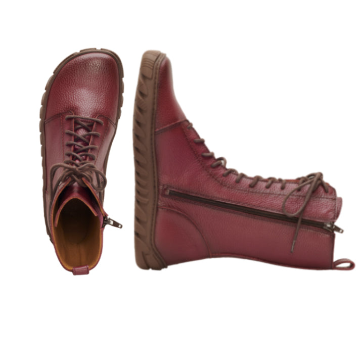 Ein Paar DOQS Bordeaux High-Top-Lederstiefel von ZAQQ aus hochwertigem Nappaleder mit braunen ULTRAGRIP-Sohlen und Schnürsenkeln. Ein Stiefel steht aufrecht und zeigt einen seitlichen Reißverschluss, während der andere mit der Öffnung nach oben liegt.