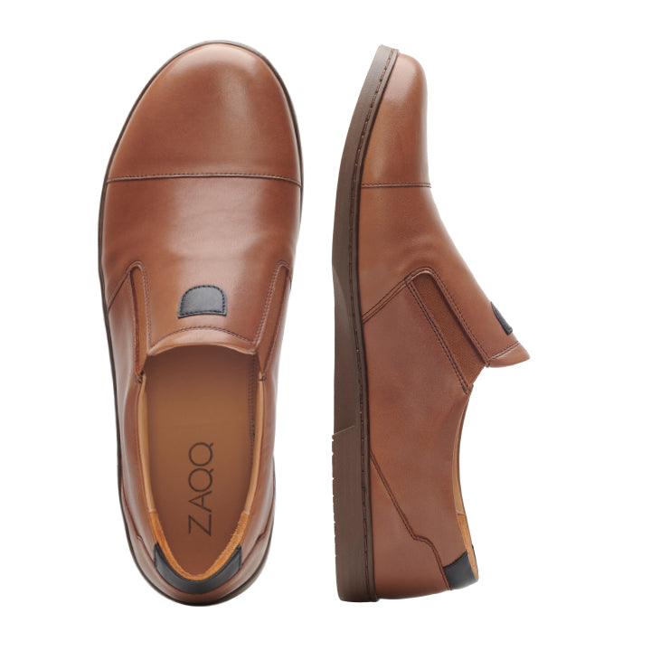 Ein Paar CLARQ Brown-Schuhe von ZAQQ, im Slip-On-Stil aus glattem Nappaleder gefertigt, wird aus mehreren Blickwinkeln gezeigt. Die Innensohle des linken Schuhs trägt den Markennamen ZAQQ. Diese bequemen, minimalistischen Schuhe haben dunkle Flecken in der Nähe der Ferse und eine leicht erhöhte Sohle für mehr Komfort.