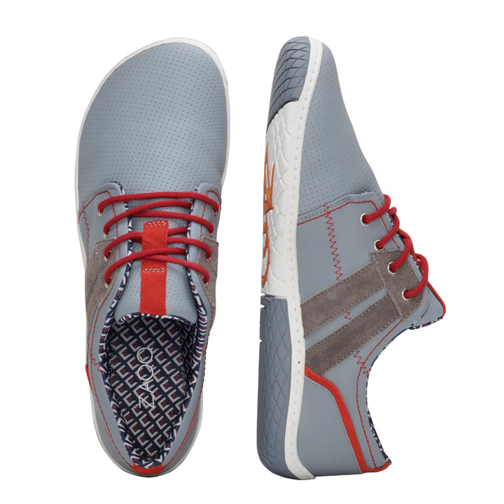 Ein Paar stylische QAPETOWN Grey-Sneaker von ZAQQ mit roten Schnürsenkeln, grauen Wildlederakzenten und einer gemusterten schwarz-weißen Innenseite. Die Schuhe werden sowohl von oben als auch von der Seite gezeigt und zeigen ihr schlankes Design und ihre strukturierte Sohle, die bei jedem Schritt Eleganz und Komfort nahtlos miteinander verbindet.