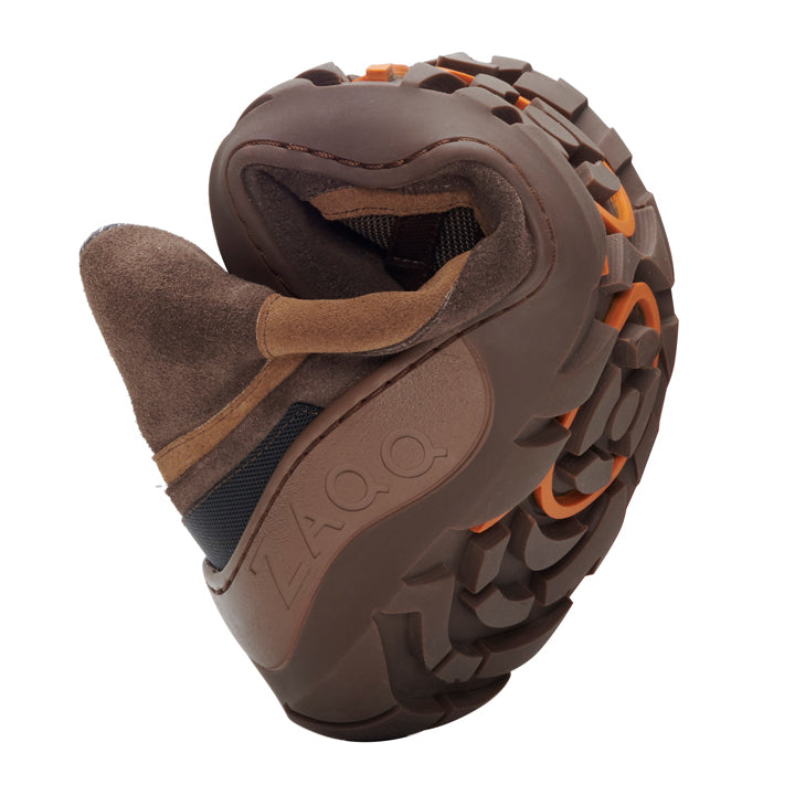 Wir präsentieren den ESQAPE Brown Waterproof von ZAQQ, einen flexiblen Wanderschuh, der sich in der Mitte biegen lässt, um seine bemerkenswerte Biegsamkeit zu demonstrieren. Er verfügt über ein robustes Profil und eine Sohle mit auffälligen orangefarbenen Akzenten, die den Outdoor-Geist perfekt einfangen. Ideal für abenteuerlustige Seelen, die auf jedem Trail sowohl Komfort als auch Stil schätzen.