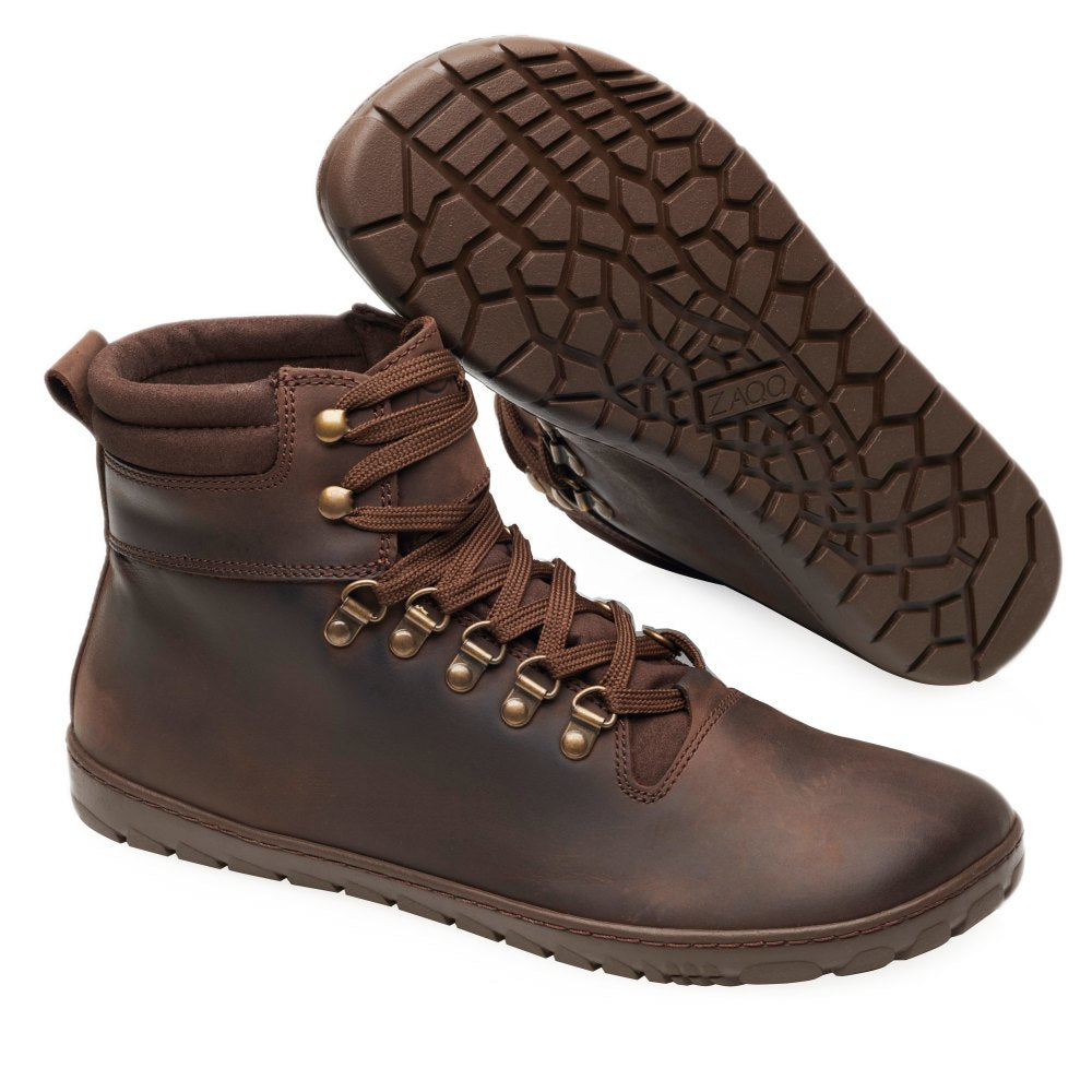 Ein Paar wasserdichte EXPEQ Brown-Wanderstiefel von ZAQQ mit strukturierten Gummisohlen. Ein Stiefel steht aufrecht und betont das Schnürdesign, während der andere geneigt ist, um das Profilmuster hervorzuheben.