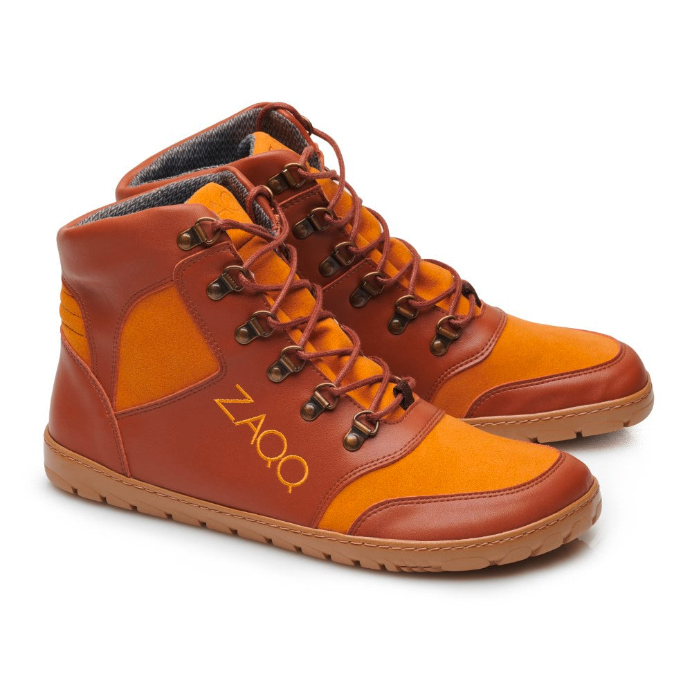 Wir präsentieren den HIQE Vegan Sierra Waterproof von ZAQQ: ein Paar braune und orangefarbene High-Top-Sneaker für umweltbewusste Abenteurer. Dieser vegane Wanderschuh hat dicke Schnürsenkel, Metallösen und eine hellbraune Sohle mit geprägtem ZAQQ-Logo. Das weiche, strukturierte Futter bietet ultimativen Komfort für Ihre Outdoor-Ausflüge.