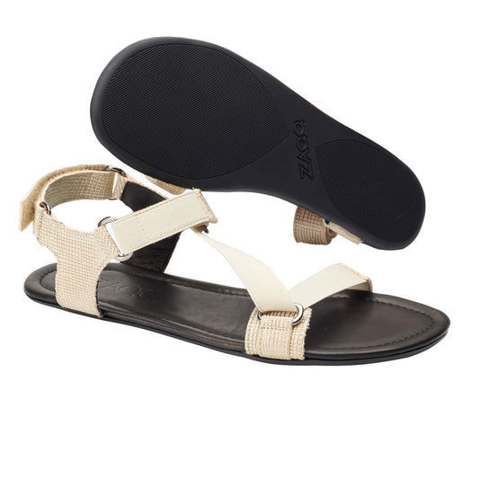 Die MIQA Gold-Sandalen von ZAQQ zeichnen sich durch ein unverwechselbares Riemensystem aus, bei dem ein Riemen flach liegt, um die elegante Draufsicht hervorzuheben, und ein anderer abgewinkelt ist, um die strukturierte Sohle und das Seitenprofil zu zeigen. Diese stilvollen Barfußsandalen sind mit Klettverschlüssen versehen und mit silbernen Schnallenakzenten verziert.