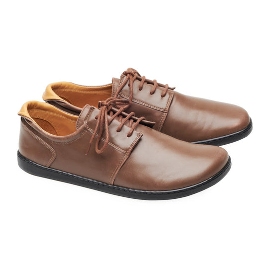 Die Schuhe „PIQUANT Nappa Dark Brown“ von ZAQQ sind aus braunem Leder mit schwarzer Sohle und hellbraunem Innenfutter gefertigt. Sie verfügen über Schnürsenkel und ein Low-Cut-Design. Die Schuhe werden auf einem Foto vor einem schlichten weißen Hintergrund präsentiert.