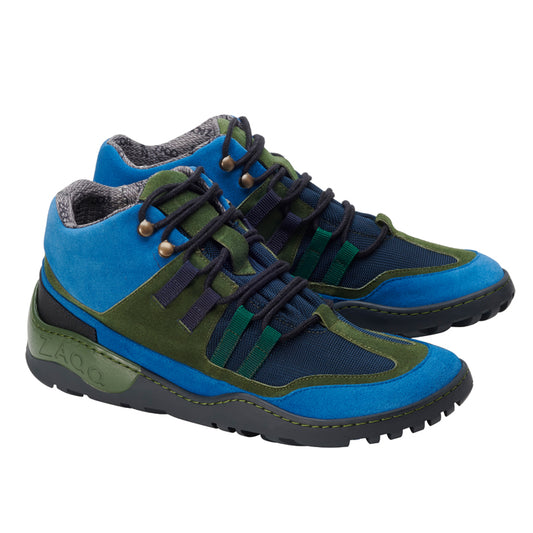 Die ESQAPE Blue Green Waterproof Sneaker von ZAQQ bestechen durch ihr leuchtend blaues und grünes Wildleder, ergänzt durch schwarzes Mesh und dunkle Schnürsenkel. Sie verfügen über das markante ZAQQ TERRA Sohlendesign für die Sohlen, während das graue wollähnliche Innenfutter für Komfort sorgt. Der Markenname ZAQQ ist prominent auf der Außensohle eingeprägt.