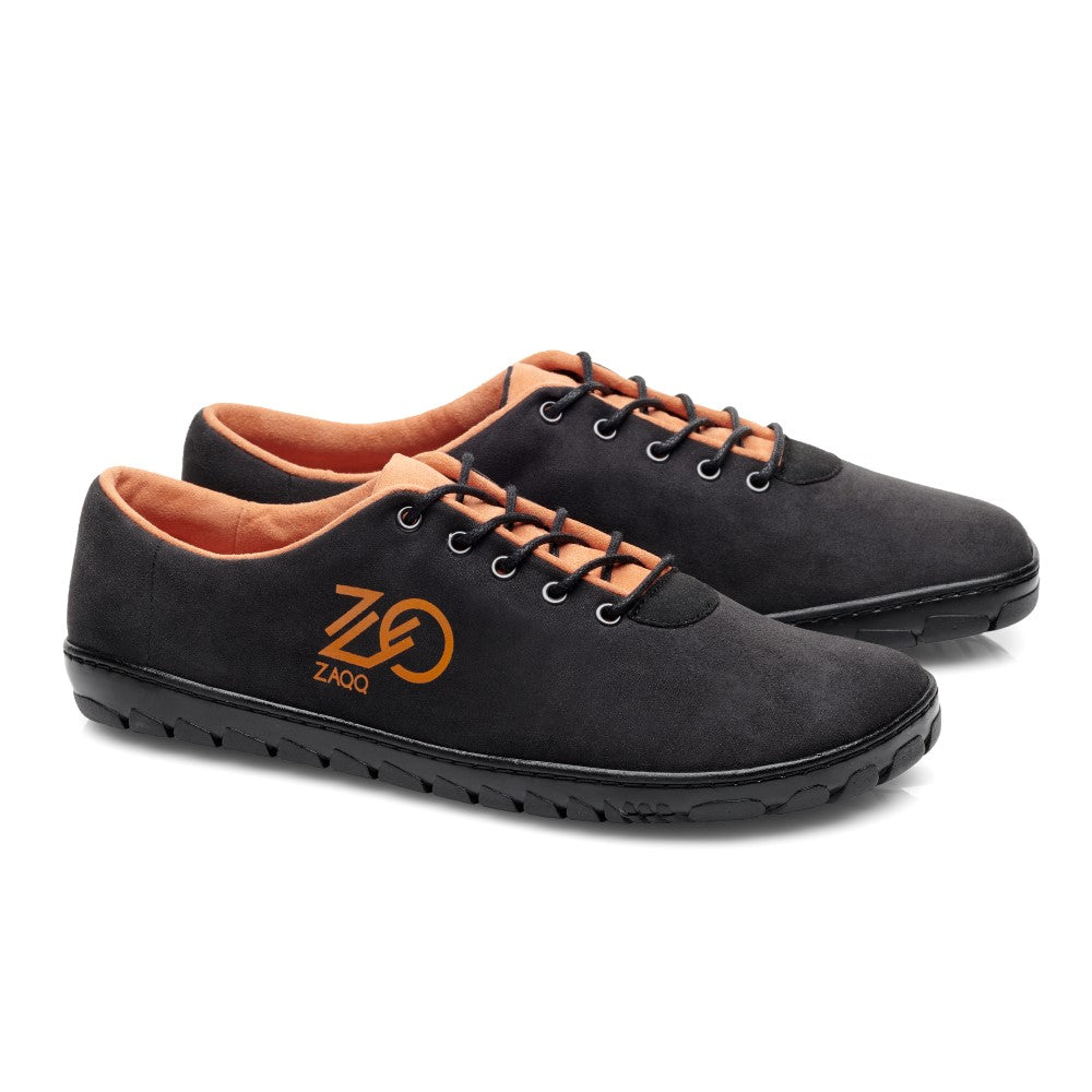 Wir präsentieren die QARO Black Orange Sneaker von ZAQQ mit einer eleganten schwarzen veganen Außenseite, ergänzt durch ein leuchtend orangefarbenes Innenfutter und schwarze Schnürsenkel. Diese stylischen Schuhe sind mit einem auffälligen orangefarbenen Logo an der Seite verziert und verfügen über flexible Kautschuk-Sohlen für ultimativen Komfort bei jedem Schritt. Die strukturierten Sohlen verleihen außerdem einen zusätzlichen Hauch von Flair.