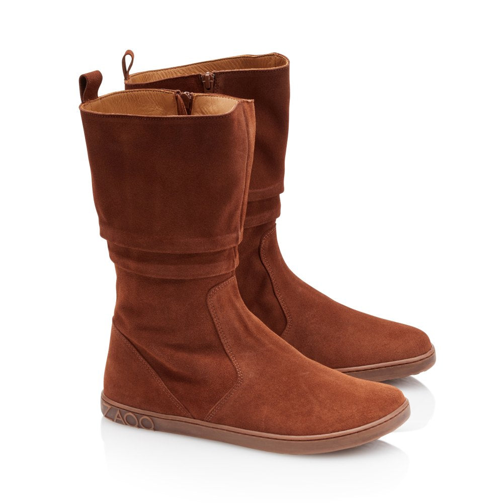 Ein Paar ZAQQ QOM Cognac-Stiefel mit halbhoher Sohle aus weichem Ziegenveloursleder in sattem Braun, mit seitlichen Reißverschlüssen und flachen Gummisohlen, in einem eleganten Design auf weißem Hintergrund.