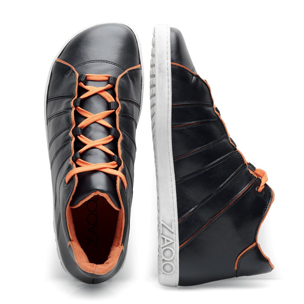 Die QQQ Mid Black Orange Sneaker von ZAQQ haben ein elegantes und dennoch auffälliges Design. Sie sind aus schwarzem Nappaleder gefertigt und haben orangefarbene Schnürsenkel und Nähte. Sie haben markante weiße Kautschuksohlen, auf denen der Markenname ZAQQ deutlich sichtbar an der Seite zu sehen ist. Ein Schuh ist von oben und der andere von der Seite zu sehen.