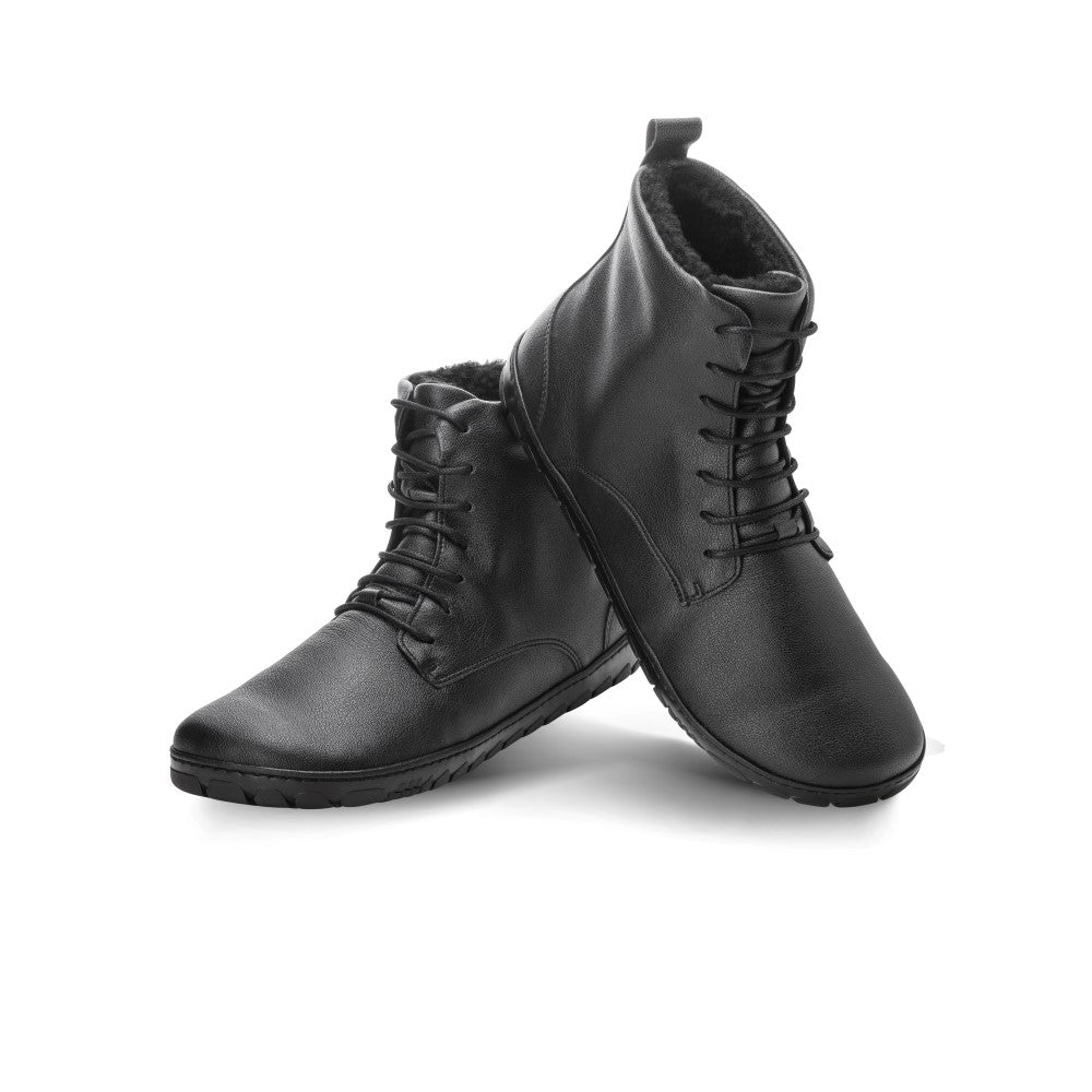 Der weiße Hintergrund bietet die Bühne für ein Paar QUINTIC Winter Vegan Black Waterproof-Stiefel von ZAQQ mit ihrem eleganten High-Top-Design und den aufwendigen Schnürsenkeln. Ein Stiefel steht aufrecht, während der andere daran lehnt, was sowohl das stilvolle Aussehen als auch die bequeme Passform hervorhebt.